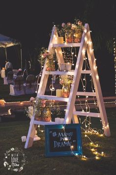 a wooden ladder decorated with flowers and fairy lights for an outdoor wedding or party decoration