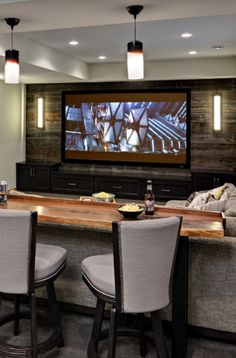 a large entertainment room with bar seating and flat screen tv on the wall above it