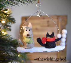 two stuffed animals hanging from a christmas tree ornament on a white snow - covered branch