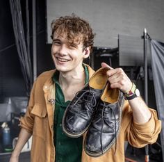 a young man holding up two pairs of shoes