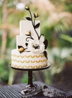 a white and yellow wedding cake with flowers on the top is sitting on a table