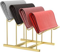 three different colored purses sitting on gold stands with each other in the same row