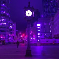 a clock tower in the middle of a city at night with purple lights on it