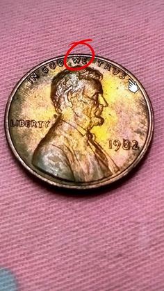 a penny with a red marker on it sitting on top of a pink cloth covered table