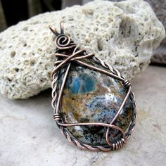 a wire wrapped pendant sitting on top of a rock