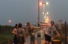 three people standing on a train platform at night