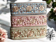 a close up of a wallet on a wooden surface with flowers in the back ground