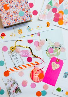 some cards and tags on a table with confetti, polka dot paper, and other items