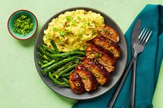 a plate with meat, mashed potatoes and green beans on it next to a fork