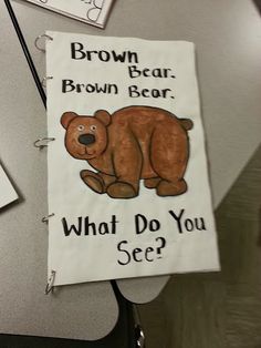 a brown bear sign hanging from the side of a wall next to a desk with papers on it