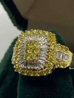 a yellow and white diamond ring sitting on top of a green cloth