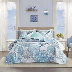 a bed room with a neatly made bed and ocean themed comforter on top of it