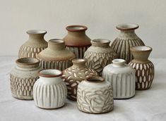 a group of ceramic vases sitting on top of a white tablecloth covered floor