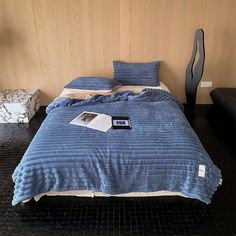 a bed with blue bedspread and pillows in a room next to a chair