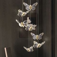 some glass butterflies hanging from the ceiling in front of a black door with a lamp on it