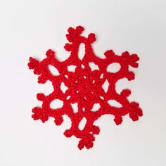 a red crocheted snowflake on a white surface