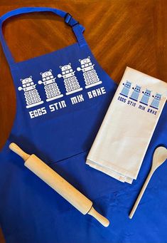 a blue apron with the doctor whos on it next to a wooden spoon