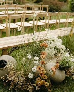 an arrangement of flowers and vases in front of rows of chairs on the grass