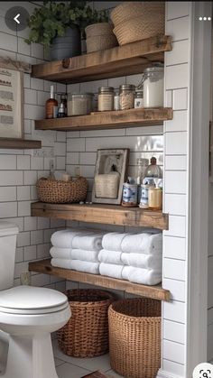 a bathroom with shelves filled with towels and other items on the shelf above the toilet