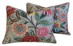 two decorative pillows with flowers on them, one is blue and the other is pink