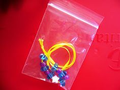 a plastic bag filled with colorful beads on top of a red surface