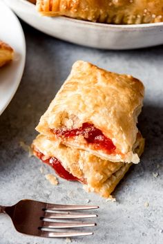 a piece of strawberry turnover sitting on top of a table next to a fork