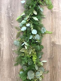 an arrangement of green plants and greenery on a wooden surface