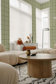 a living room with couches, tables and chairs in front of green plaid wallpaper