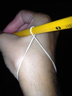 a person holding a yellow pencil in their left hand and string wrapped around the end