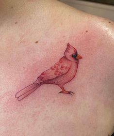 a small red bird tattoo on the back of a woman's shoulder and chest