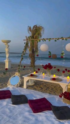 a table set up on the beach with flowers and candles