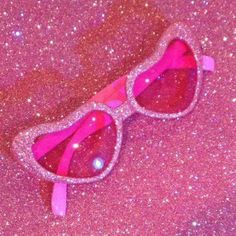 a pair of pink sunglasses laying on top of glitter