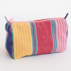 a multicolored striped cosmetic bag sitting on a white surface with the zipper open