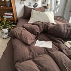 an unmade bed with brown sheets and pillows