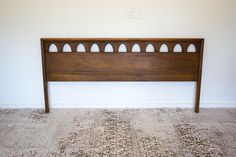 a wooden headboard sitting on top of a carpeted floor next to a wall