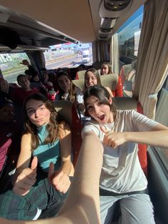 a group of people riding on the back of a bus with their hands in the air