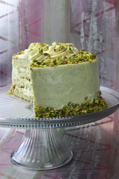 a cake with white frosting and green sprinkles sitting on a glass plate