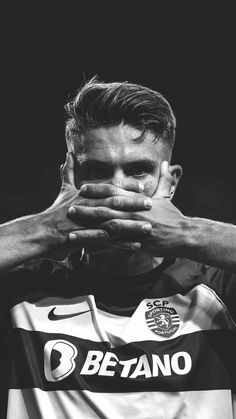 a black and white photo of a soccer player covering his face