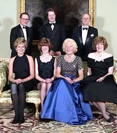 a group of people in formal wear sitting on a couch together, posing for a photo