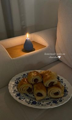 a plate with rolls on it next to a lit candle