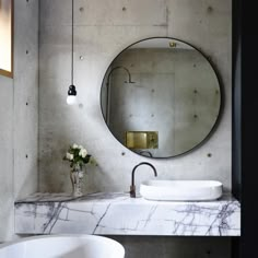 there is a bathroom with marble counter tops and white furniture in the room, along with a round mirror on the wall