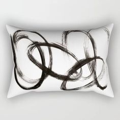 a black and white rectangular pillow with an abstract design on the front, featuring curved lines