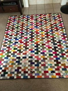 a multicolored patchwork quilt on the floor