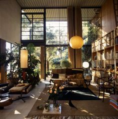 a living room filled with lots of furniture next to a large window covered in books