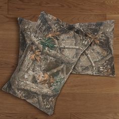 two camouflage pillows on top of a wooden floor