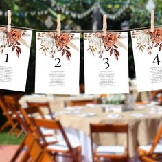 the table numbers are hanging from clothes pins with flowers and leaves on them, along with place cards for seating