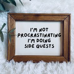 a framed sign that says i'm not procrastinating i'm doing side quests