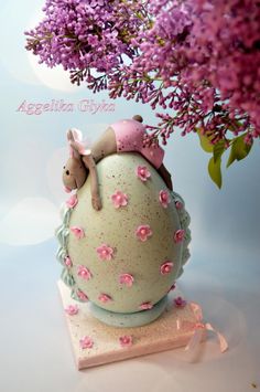 a ceramic figurine sitting on top of a white ball with pink flowers in the background