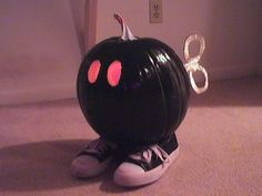 a black pumpkin sitting on top of a floor next to a white wall and door