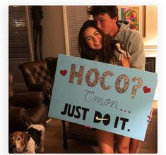 a man and woman holding a sign that says hoco? i'm not just do it